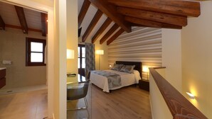 A bedroom with a wooden ceiling, a bed with patterned bedding, a bedside table, and a chair. - Hotel Los Arcos (Ainsa)