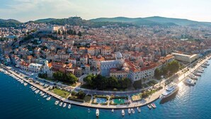 Vue aérienne d’une ville côtière, avec ses bâtiments historiques, son port de plaisance et un imposant dôme.