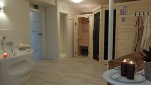 Une salle de bain avec une baignoire, un lavabo et un porte-serviettes. Une porte en bois donne accès à une autre pièce.