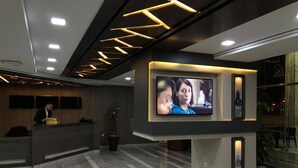 Un espace d’accueil moderne, doté d’un grand écran de télévision, d’un comptoir de réception et d’un sol en marbre.