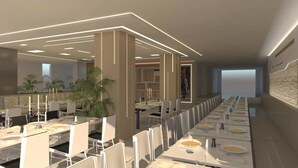 Un espace de restauration moderne avec de longues tables et des chaises, une vue sur la mer et un aménagement intérieur minimaliste.