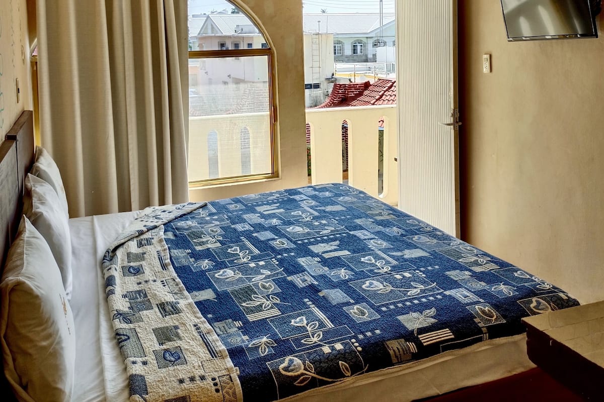 Un dormitorio con cama, cortinas, una ventana y un televisor.