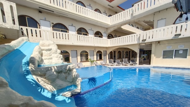 A swimming pool with a rock formation and a covered area with chairs. - Hotel Playa de Oro (Boca del Río)