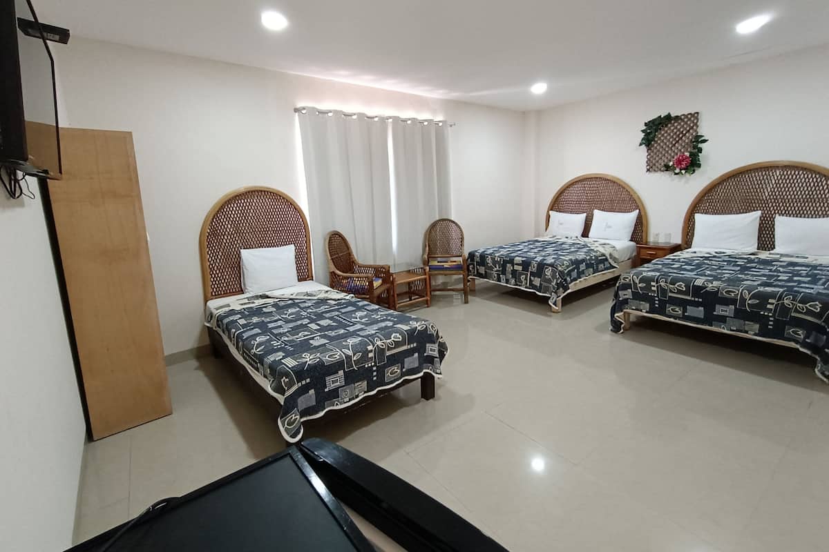 Habitación de hotel con tres camas, un escritorio y una silla.