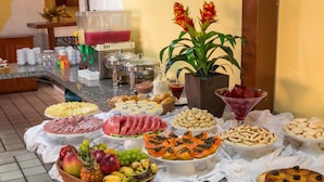 A buffet with various food items including fruits, cheeses, meats, and desserts. - Chaua Porto Hotel (Porto Seguro)