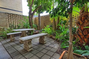 Relax in a serene patio surrounded by lush greenery and a brick wall with a lattice design.