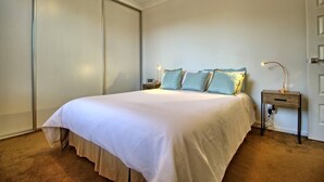 Een slaapkamer met een bed, nachtkastjes en een kledingkast.
