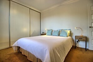 A bedroom with a bed, bedside tables, and a wardrobe.
