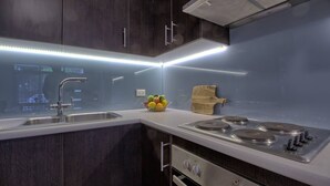 Een moderne keuken met donkerhouten kastjes, een roestvrijstalen spoelbak, een gasfornuis en een fruitschaal.