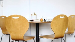 Ein Konferenzraum mit einem Holztisch und vier Stühlen mit ausgeschnittenen Griffen.