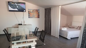 Een hotelkamer met een bed, een bureau met stoel, een aan de muur bevestigde televisie en een schilderij.