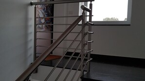 Een moderne trap met een metalen leuning en zwarte treden, leidend naar een ruimte met een groot raam en een deur met een kleurrijk schilderij.