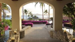An arched pathway leading to a beach with palm trees and a view of the ocean. - Casa Del Mar Beachfront Luxury 2BR Condo (San Jose del Cabo)