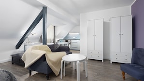 A modern loft apartment with a dining area, a sofa, a small round table, and a wardrobe. - Trip Inn Boutique Rubens Essen (Essen)