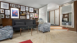 A modern living room with a grey sofa, a zebra-patterned armchair, a glass coffee table, and a red rug. - Trip Inn Boutique Rubens Essen (Essen)
