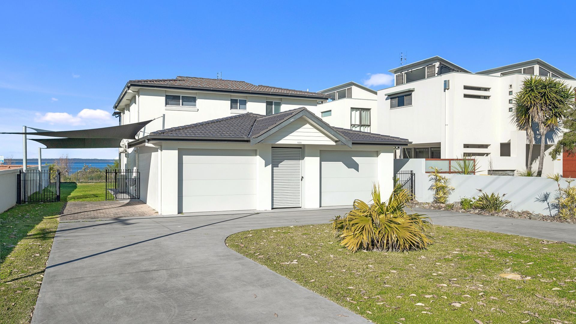 A modern residential building with a garage, a covered driveway, and a well-maintained lawn.