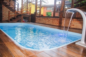 An indoor swimming pool with a clear water surface, surrounded by wooden flooring and brick walls.