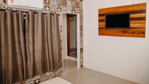 A room with patterned walls, a mounted TV, and a sliding door. - Pousada Armação das Baleias (Penha)