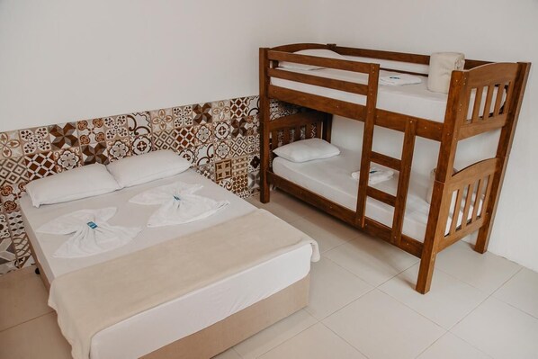 A bunk bed with a wooden frame and white bedding, a patterned tile wall, and a plain white floor.