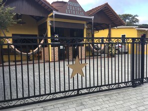 A building with a sign reading 'POUSADA QUATRO ESTRELAS' and a star-shaped decoration on the gate.