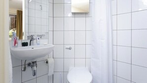 A bathroom with a white sink, mirror, and toilet. - Platt Hall - Campus Accommodation (London)