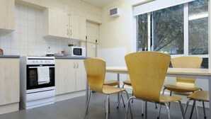A modern kitchen with a built-in oven, microwave, and a window providing a view of the outdoors. - Platt Hall - Campus Accommodation (London)