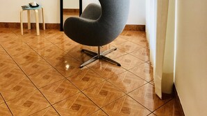 A modern room with a unique curved chair, a small table with a cup, and a mirror on the wall. - InkaHuset Pacasmayo (Callao)