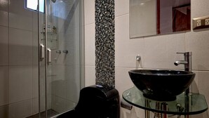 A modern bathroom with a glass shower enclosure, a black vessel sink, and a mosaic tile backsplash. - InkaHuset Pacasmayo (Callao)