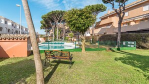 Un patio con piscina, bancos y árboles.