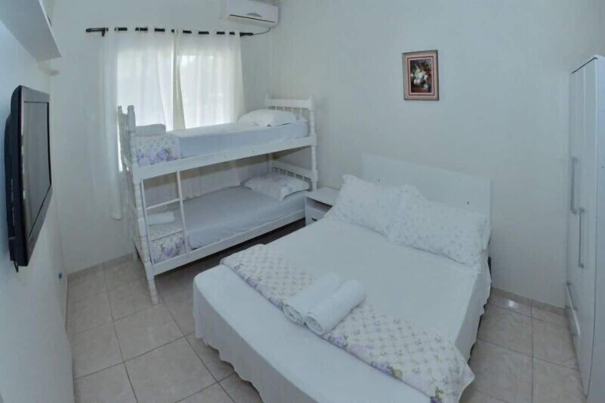 A bedroom with bunk beds, a bed, a television, and a picture on the wall.