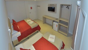 Habitación de hotel con dos camas, televisión, nevera pequeña y armario.