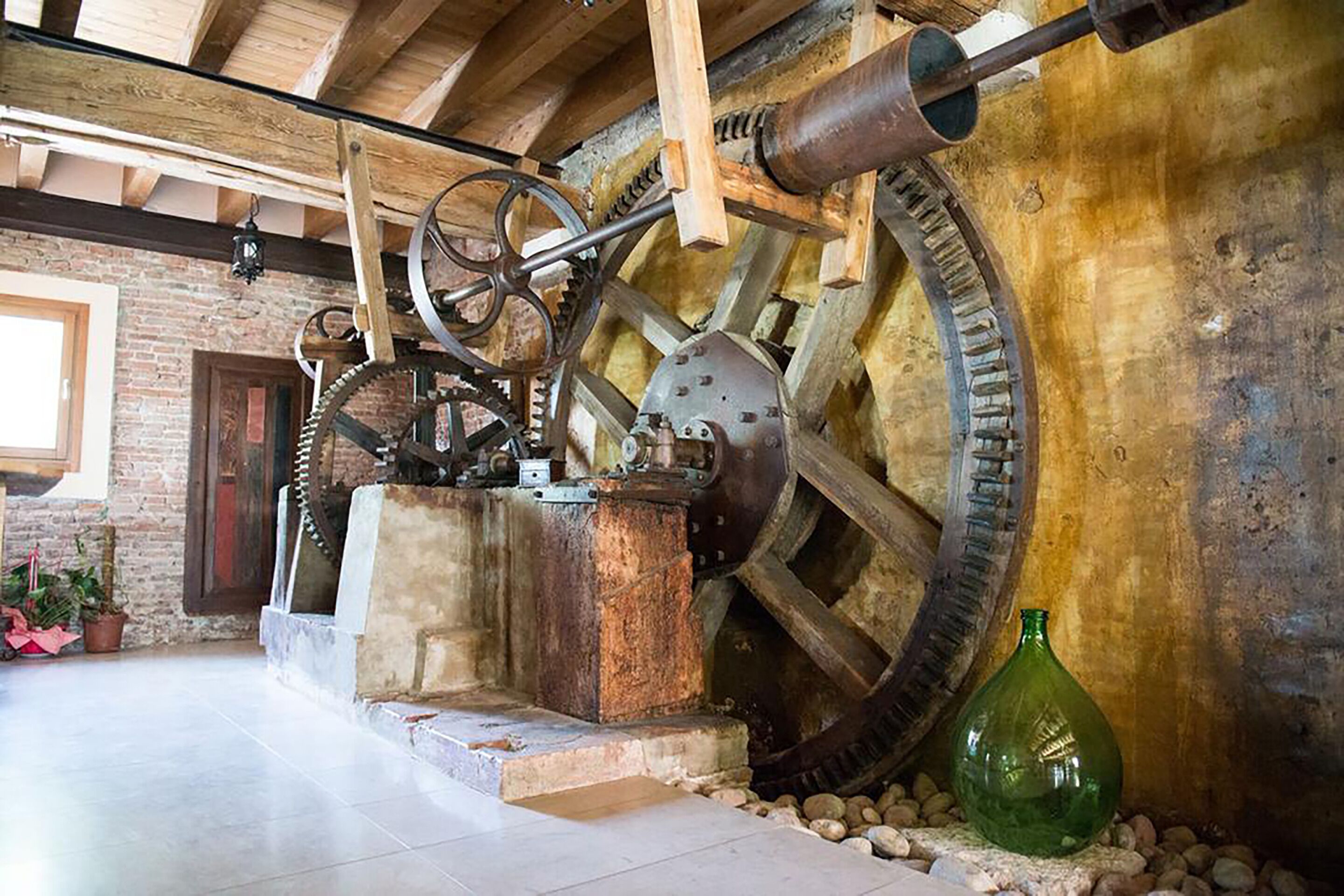 An indoor exhibit with large mechanical gears and a vintage green bottle.
