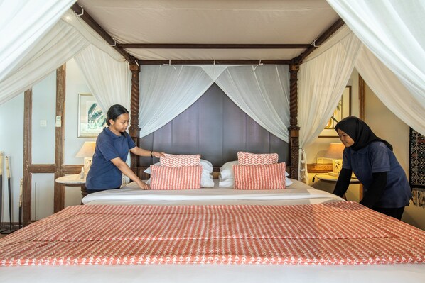 A neatly made bed with a patterned bedspread, two pillows, and a canopy.