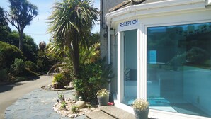 A reception area with a clear glass door, potted plants, and a stone pathway leading to the entrance. - Mounts Bay Caravan Park (Marazion)