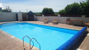 A swimming pool with a blue interior, a pool ladder, and a few lounge chairs. - Mounts Bay Caravan Park (Marazion)
