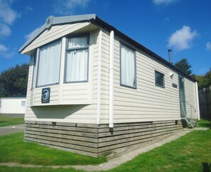 A mobile home with a front porch, large windows, and a garage door. - Mounts Bay Caravan Park (Marazion)