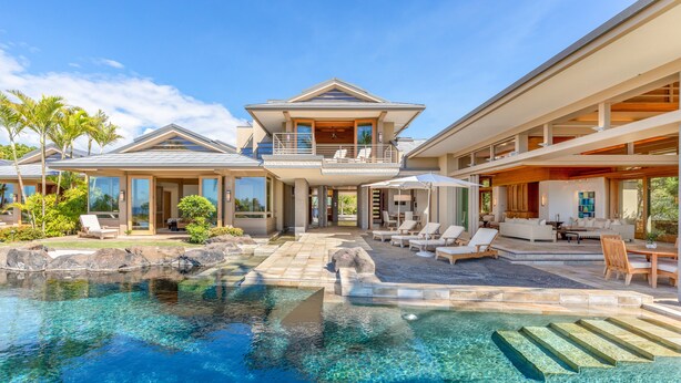 Un resort di lusso con una grande piscina, zone relax all'aperto e un giardino curato.