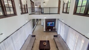 Amplia sala de estar con techo alto, balcón y televisor sobre un mueble.