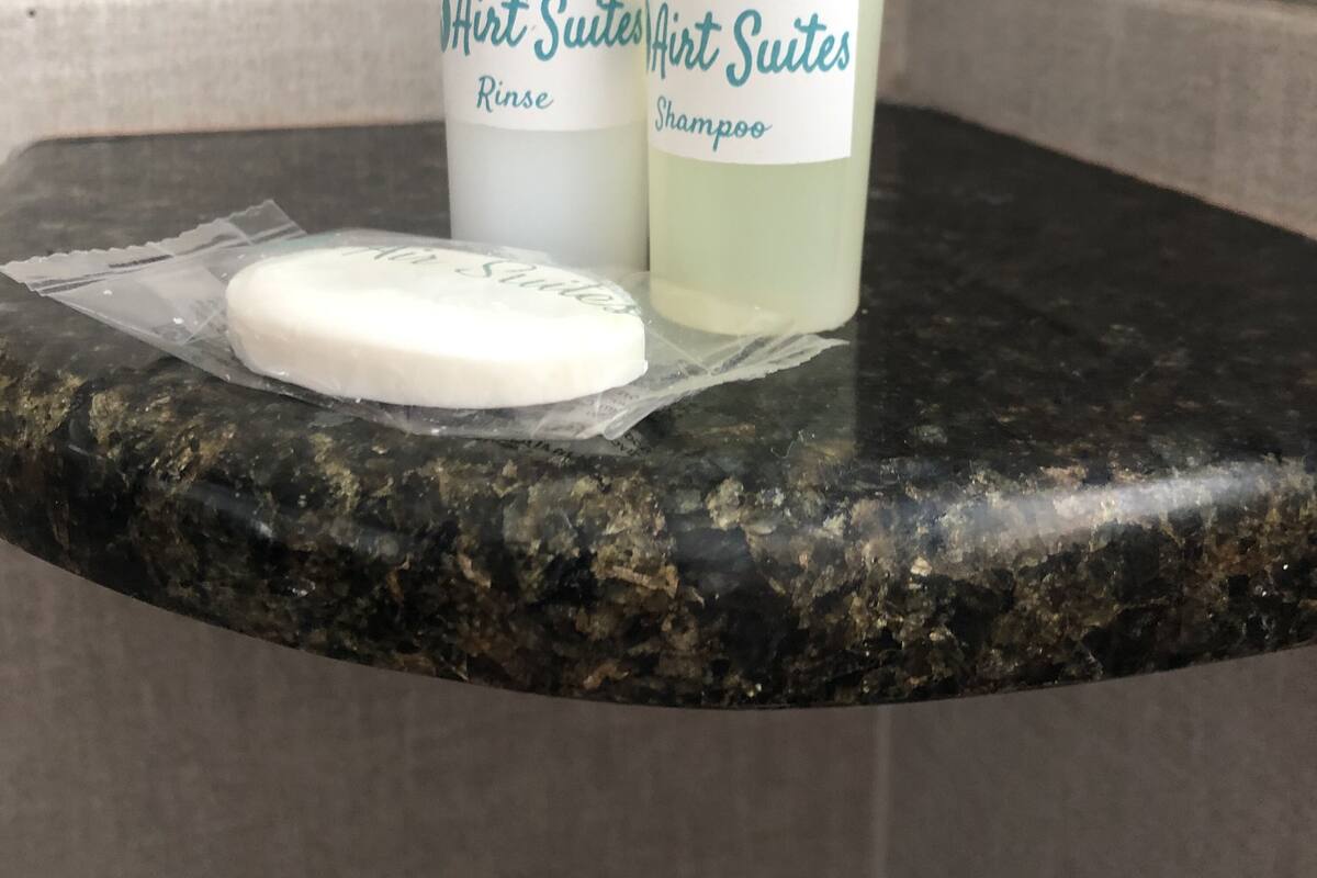Two bottles of Airt Suites shampoo and rinse on a granite countertop.
