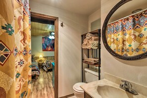 A bathroom with a toilet, sink, and towel rack. There is a patterned curtain and a mirror above the sink. - Ruidoso Condo w/ 2 Private Decks & Hot Tub! (Ruidoso)