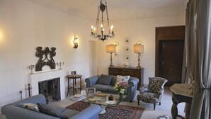 A living room with a fireplace, a chandelier, and a sofa set. - Antica Dimora La Portazza (Marsala)