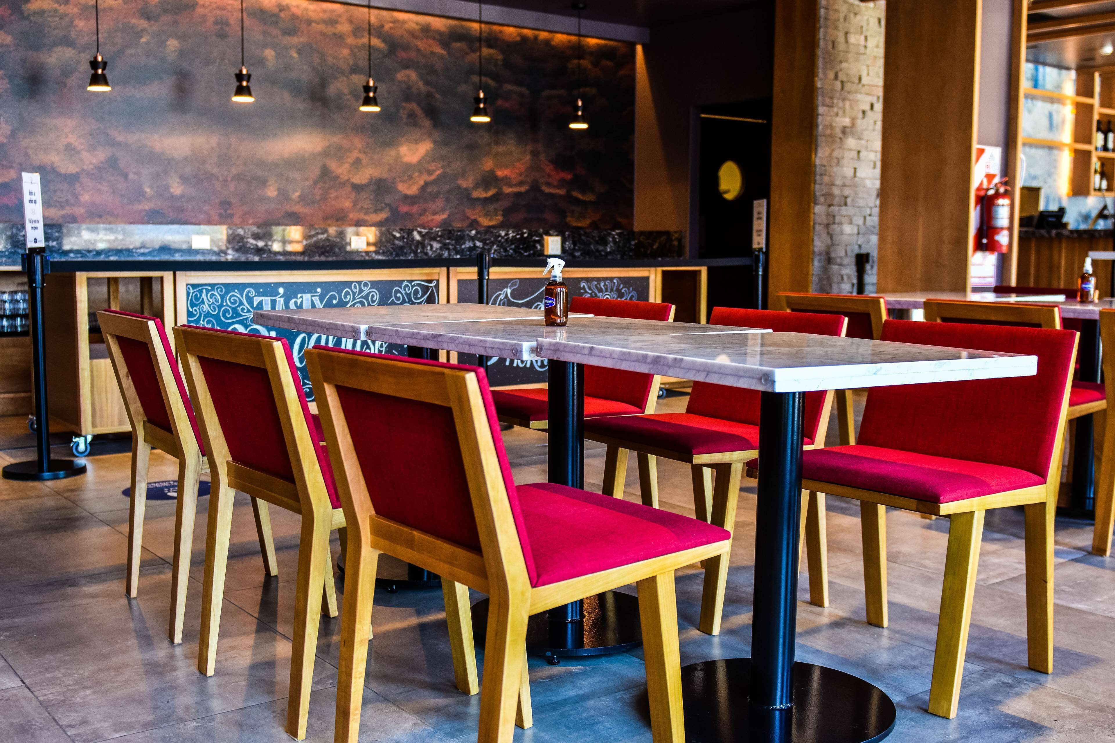 Un restaurant avec des chaises en bois et des coussins rouges, une table en marbre et des lampes suspendues.