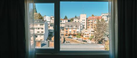 A window with a view of a residential area, including buildings and trees.