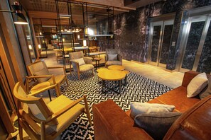 Un área de descanso moderna con un sofá, sillas, una mesa de centro y un piso estampado.