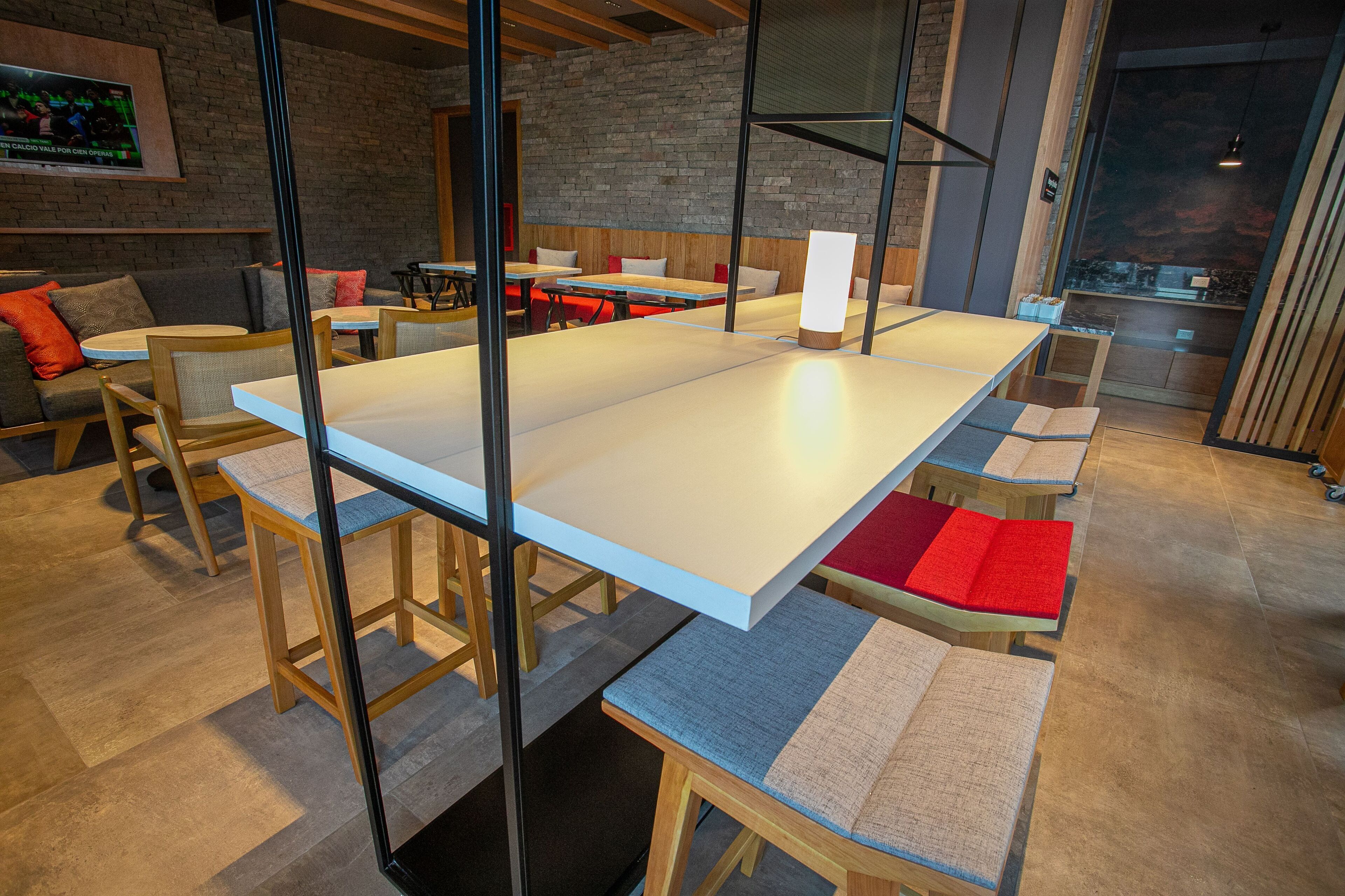Ein modernes Interieur mit einem langen Tisch, Holzsesseln und einer Ziegelwand.