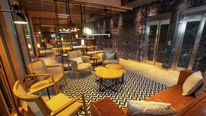 A modern lounge area with seating arrangements, a coffee table, and a patterned floor. - Hampton by Hilton Bariloche (San Carlos de Bariloche)