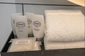 Ein Badezimmer mit Pflegeprodukten, darunter Shampoo, Conditioner und ein Handtuch.