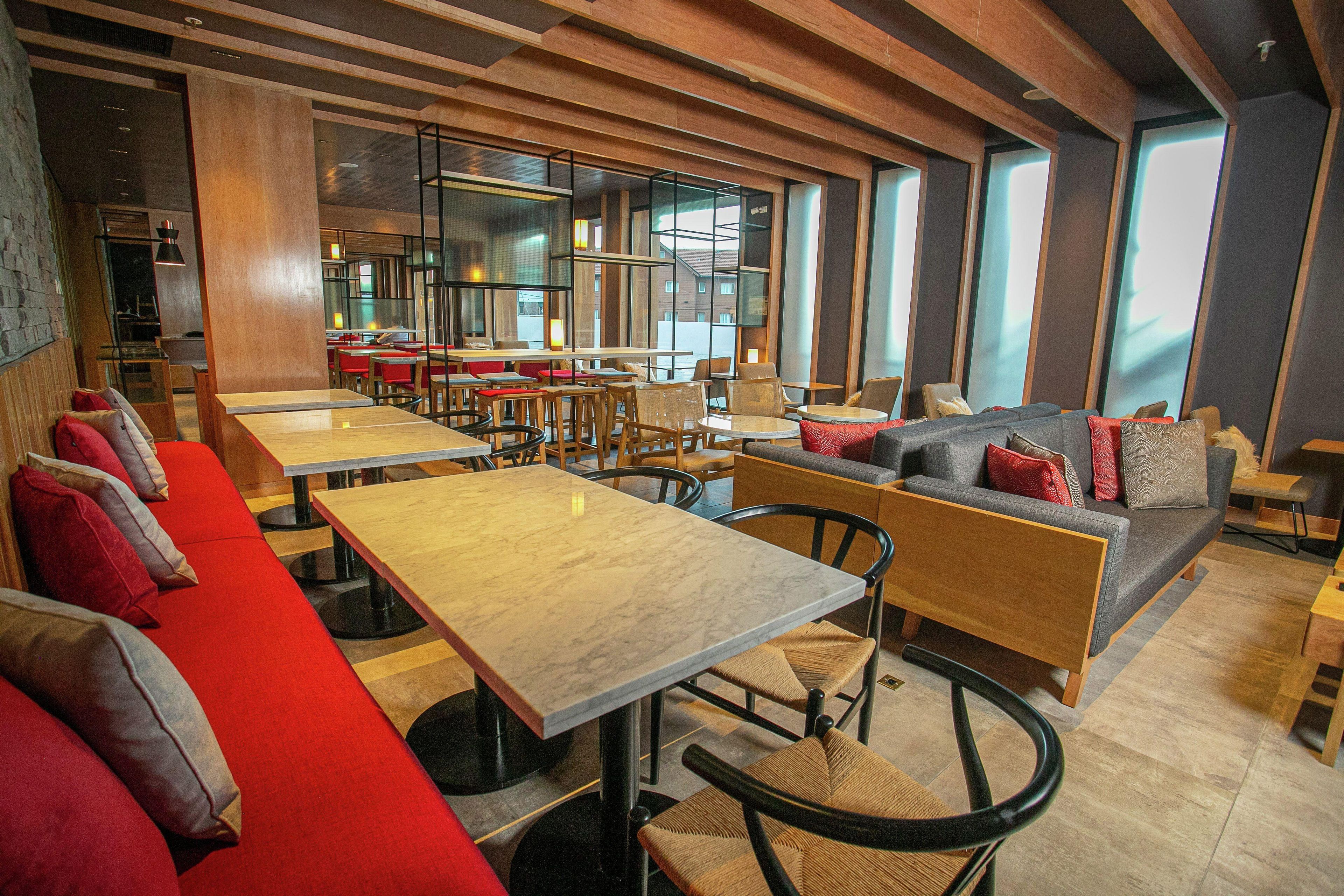 A modern restaurant interior with high tables, booths, and a mix of seating arrangements.