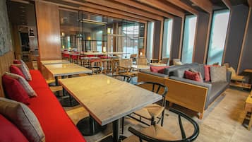 A modern restaurant interior with high tables, booths, and a mix of seating arrangements.