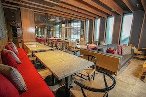 A modern restaurant interior with high tables, booths, and a mix of seating arrangements.